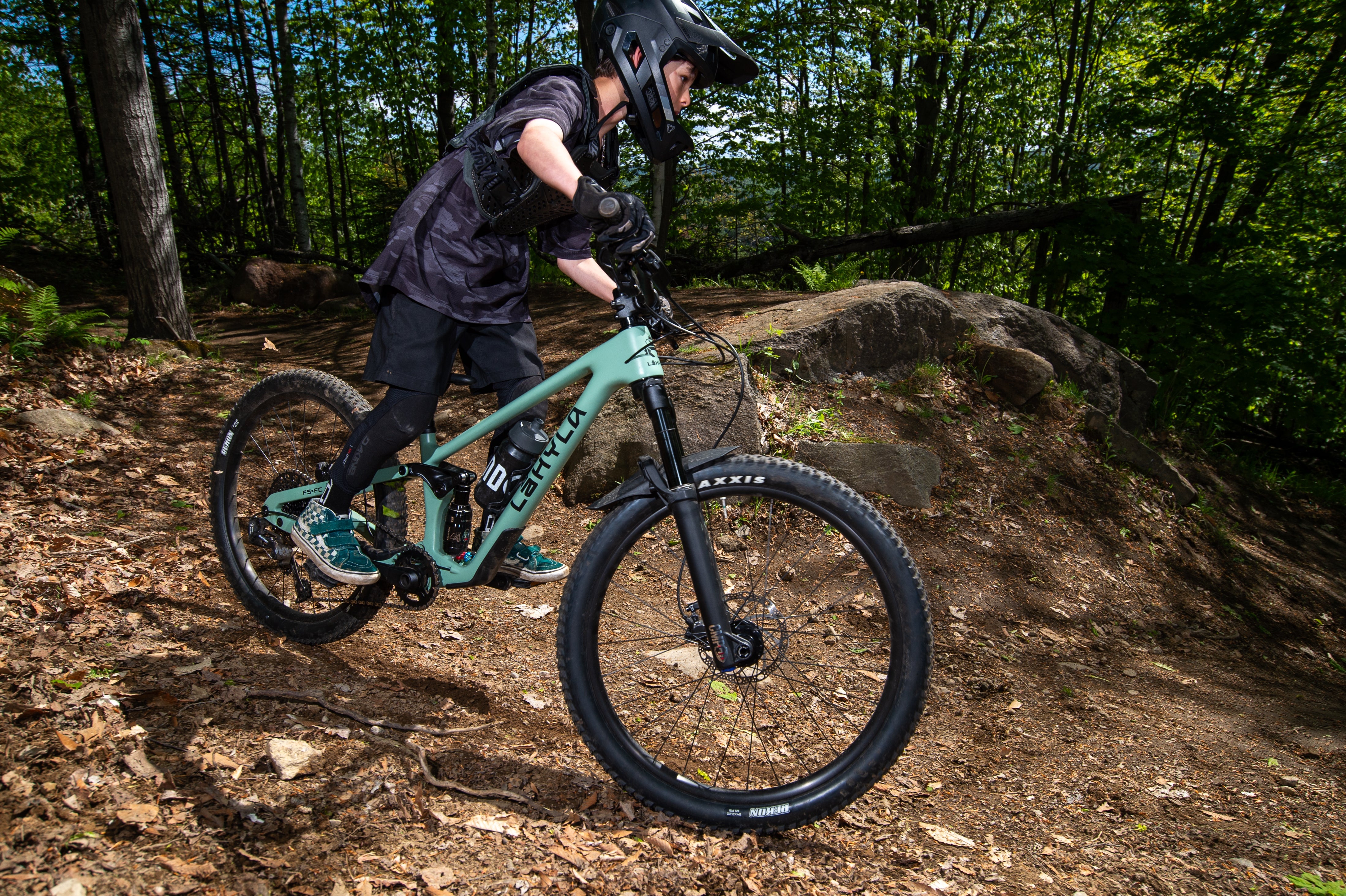 Kid riding the Lahyla Drew 24 full suspension bike on a forest trail