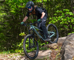 Kid riding the Lahyla Drew Mullet 26x24 over rocks on a forest trail